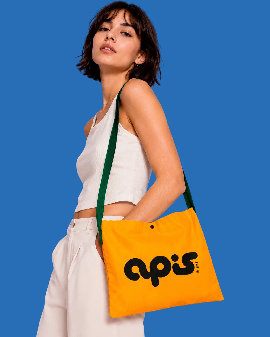 Una ragazza porta a tracolla una musette arancione con il logo Apis, su fondo azzurro